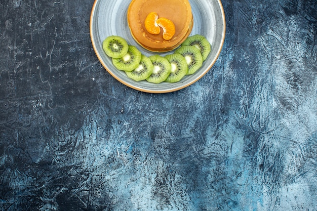 Media foto de esponjosos panqueques estilo americano hechos con yogur natural servido con kiwi en un plato sobre fondo de hielo