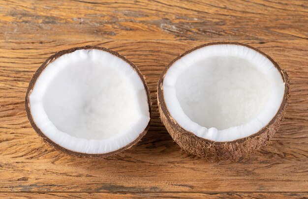 Media fruta de coco agrietada sobre mesa de madera