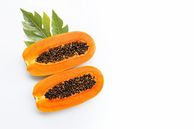 Media fruta de papaya con hojas sobre fondo blanco.