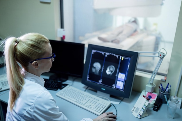 Médica analisando os resultados da ressonância magnética cerebral de um paciente no monitor do computador na sala de controle