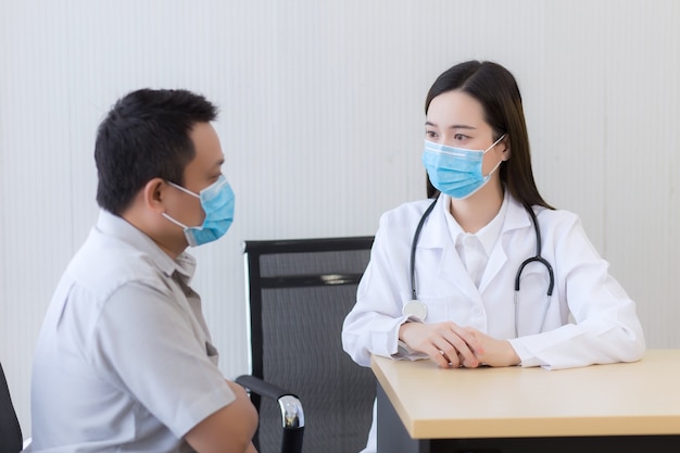 Médica asiática falando com um paciente do sexo masculino sobre sua dor e sintomas
