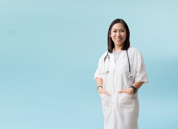 Médica asiática posando e sorrindo isolada em fundo azul com caminhos de recorte para trabalho de design espaço livre vazio