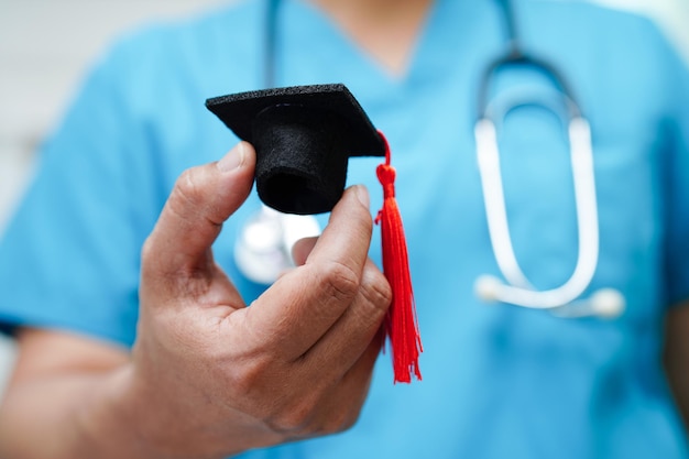 Médica asiática segurando chapéu de formatura no hospital conceito de educação médica