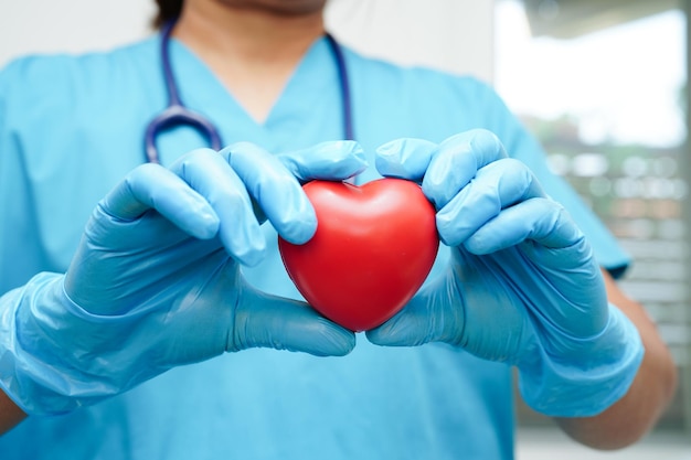 Médica asiática segurando coração vermelho para a saúde no hospital