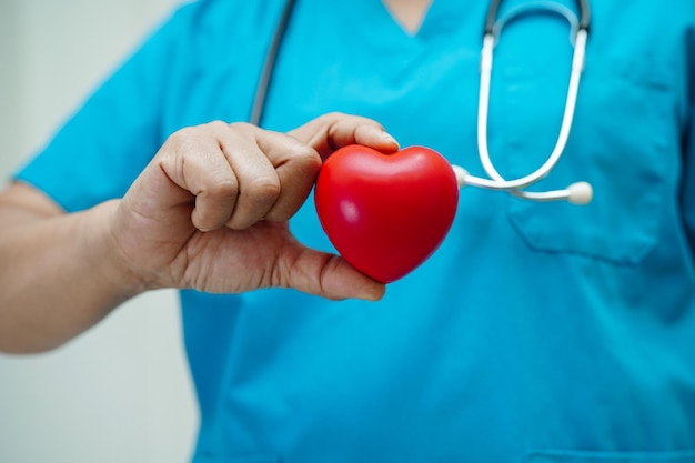 Médica asiática segurando coração vermelho para saúde no hospital