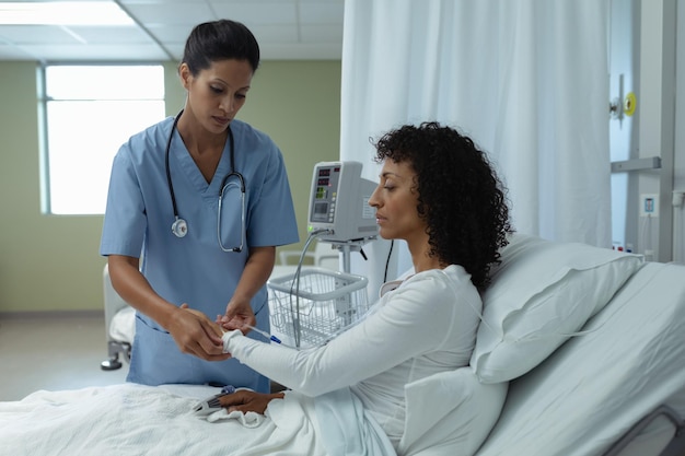Foto médica colocando un goteo intravenoso en la mano de una paciente en la sala