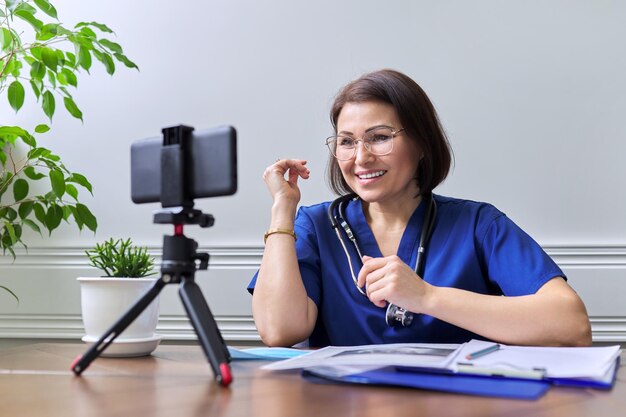 Médica com estetoscópio consultando on-line usando um smartphone em um tripé