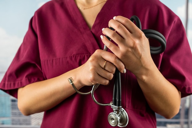 Foto médica com estetoscópio nas mãos em roupas está de pé em um hospital de prestígio