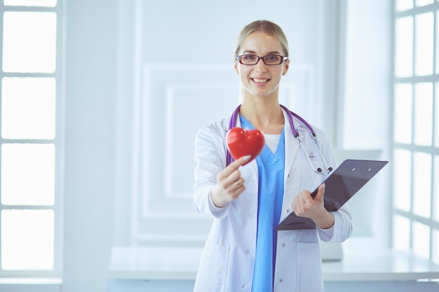 Médica com estetoscópio segurando o coração.