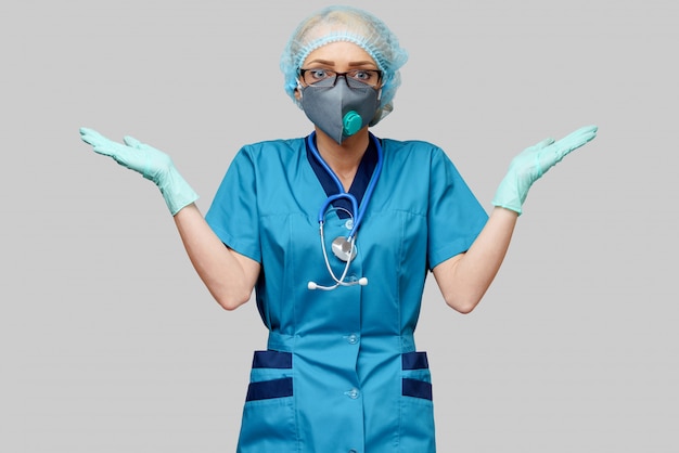 Médica com estetoscópio usando máscara protetora e luvas de látex sobre parede cinza clara