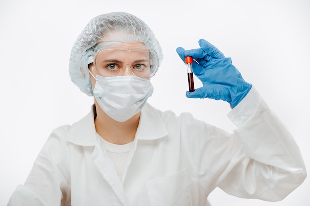 Médica com óculos de proteção segurando um tubo de amostra de sangue para fazer teste de coronavírus na clínica