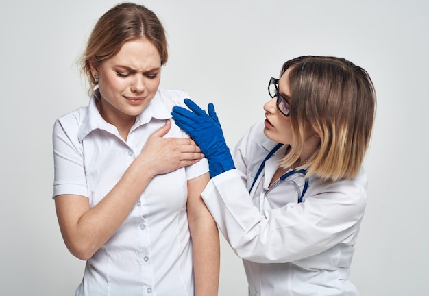 Médica com um vestido de médico e luvas azuis examina um paciente em uma visão recortada