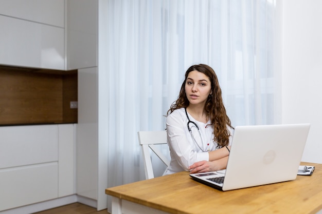 Médica consulta online usando laptop vestindo roupas médicas