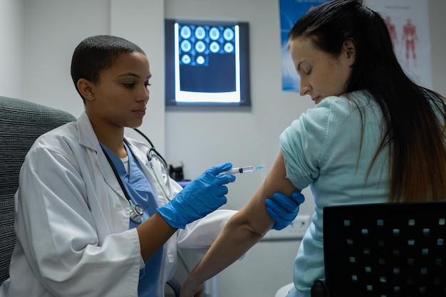 Médica dando injeção a pacientes do sexo feminino no hospital