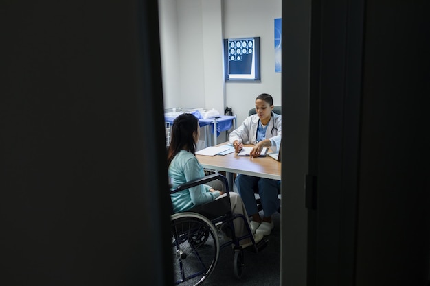 Foto médica dando receita a uma paciente com deficiência na secretária