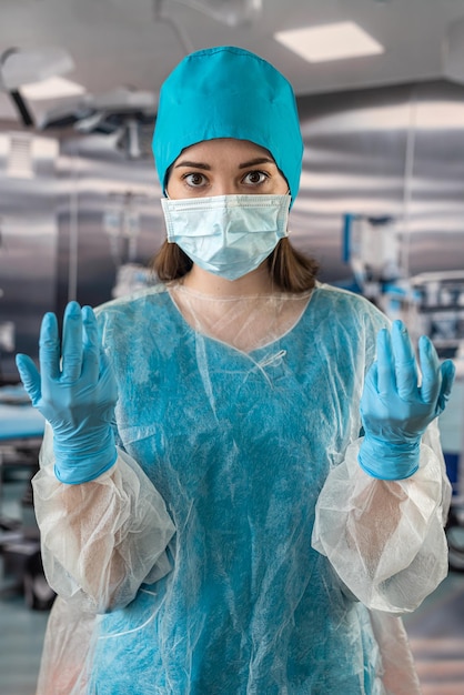 Médica de casaco azul segurando o estetoscópio e pílulas na mão enquanto está em operação