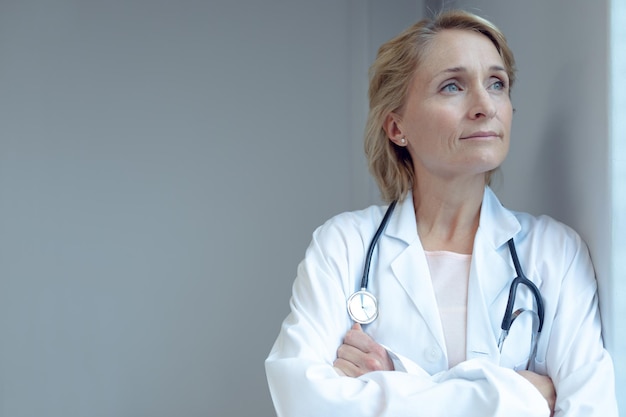 Médica de pé com os braços cruzados no hospital