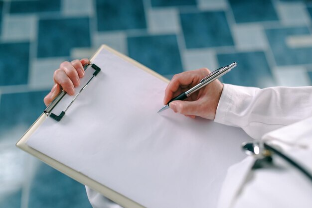 Foto médica de uniforme branco escrevendo em papel clipboard