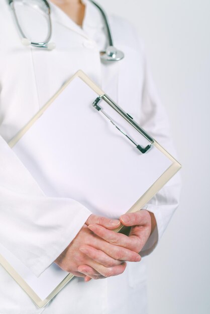 Foto médica de uniforme branco posando com um bloco de papelão em branco