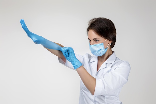 Médica de uniforme branco usando máscara e luvas de borracha