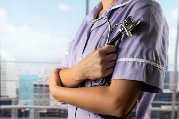 Médica de uniforme com um estetoscópio nas mãos no fundo de um hospital