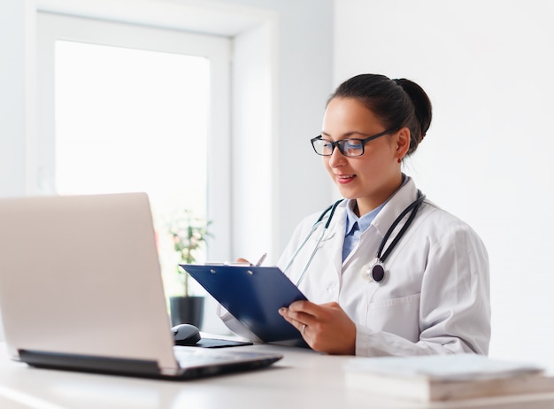 Médica de uniforme com um laptop