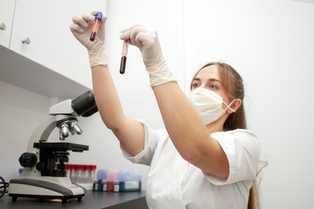 Médica de uniforme e máscara médica segura tubos de ensaio com exames de sangue no laboratório
