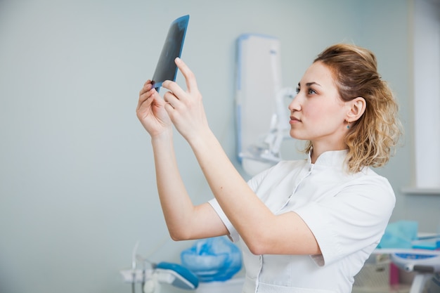 Médica dentista examinando o raio-x da mandíbula humana. estomatologista profissional, verificando a imagem de raio-x odontológico no escritório da clínica.