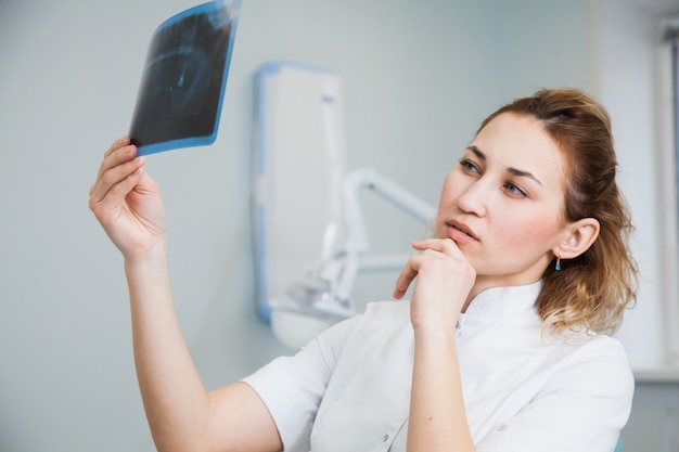 Médica dentista examinando o raio-x da mandíbula humana. Estomatologista profissional, verificando a imagem de raio-x odontológico no escritório da clínica.