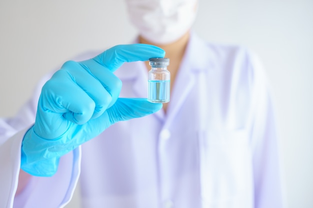 Foto médica em laboratório segurando uma garrafa com um líquido azul