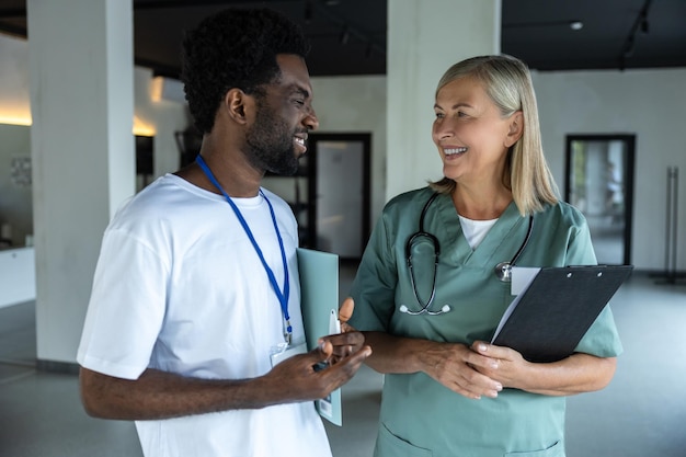 Médica em roupa médica com um estagiário afro-americano na clínica