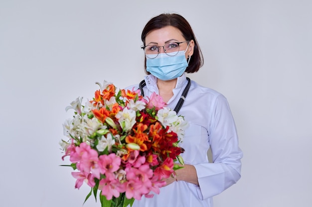 Médica em uma máscara de proteção médica no rosto e um buquê de flores