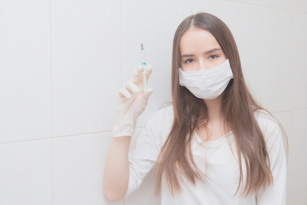 Médica em uma máscara segura uma seringa com remédio na mão antes de uma injeção