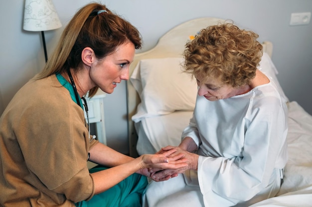 Médica encorajando paciente idoso segurando as mãos dela