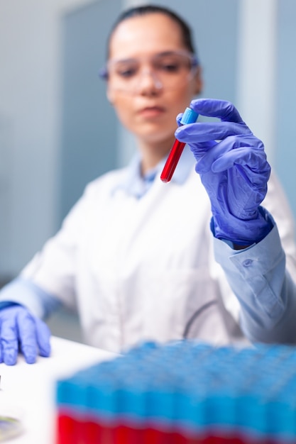 Foto médica especialista segurando vacutainer de sangue analisando experiência em infecção de dna