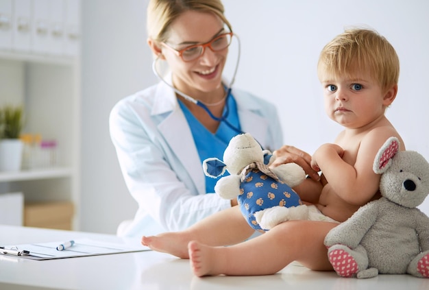 Foto médica está ouvindo criança com um estetoscópio na clínica