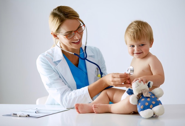Foto médica está ouvindo criança com um estetoscópio na clínica