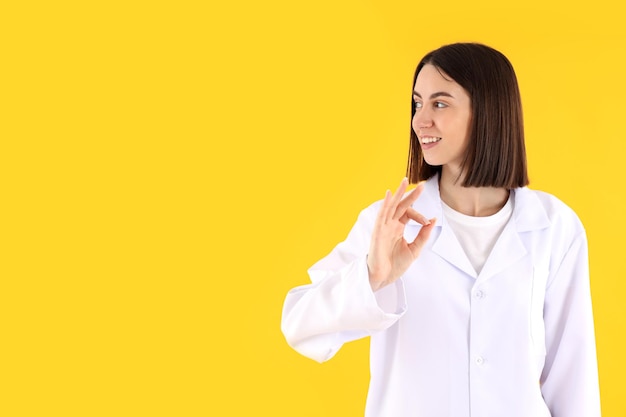 Médica estagiária atraente em fundo amarelo