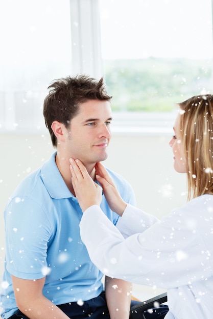 Foto médica examinando a garganta de uma paciente feliz sentada em seu escritório com neve caindo
