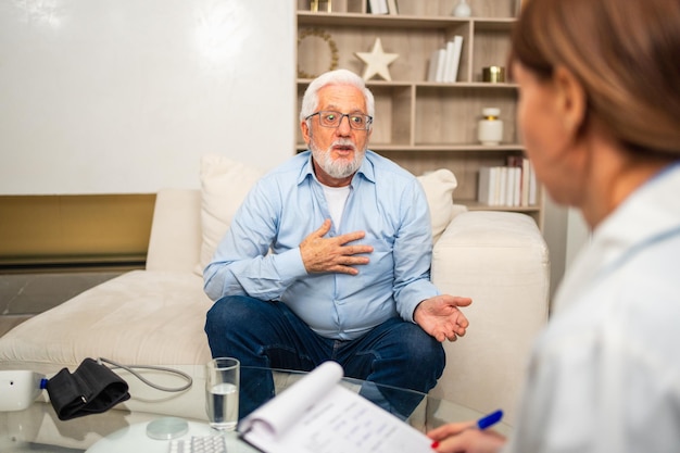 Médica examinando homem mais velho no consultório médico ou em casa, paciente e médico têm