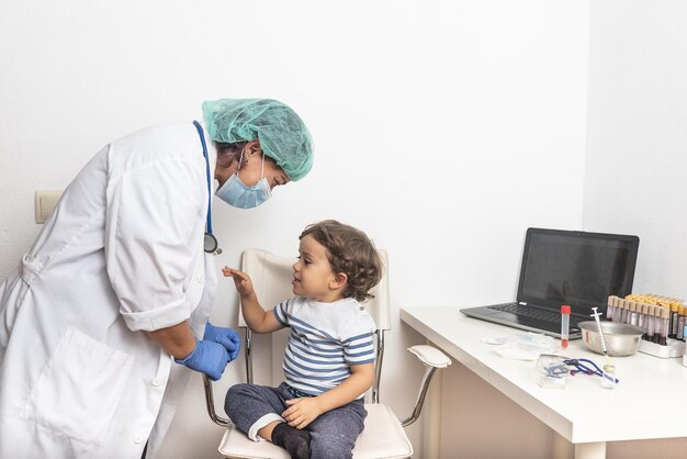 Médica examinando a un niño niño pequeño