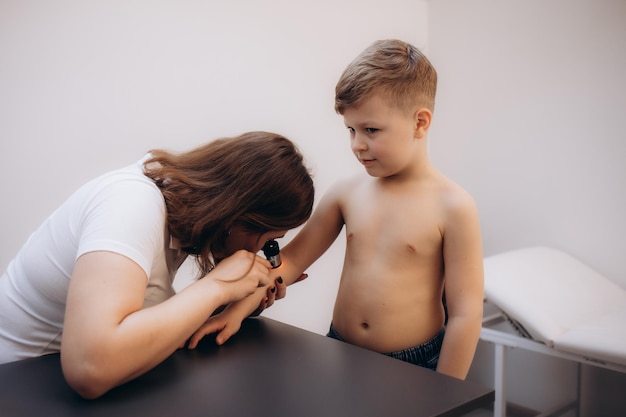 Médica examinando la piel de un niño con un dermatoscopio