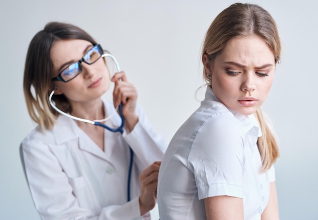 Médica feliz examina paciente do sexo feminino em modelo de saúde de camiseta branca