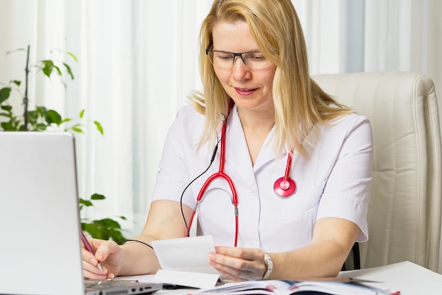 Médica feminina mostrando a imagem do paciente da imagem de ultrassom de seu bebê no teletratamento do laptop