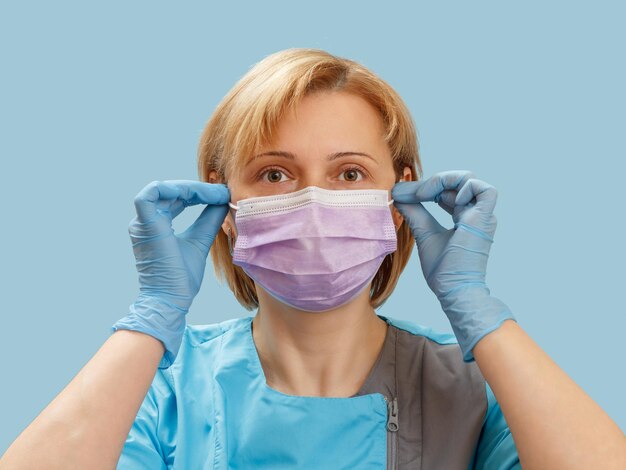 Médica con guantes de látex y mascarilla médica como protección contra virus en el aire