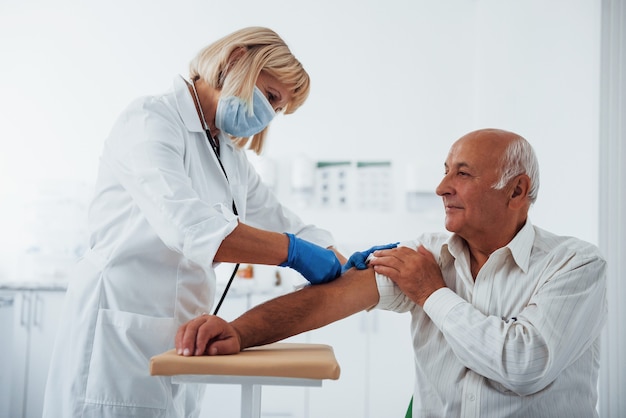 Médica injetando paciente sênior do sexo masculino com seringa na clínica.