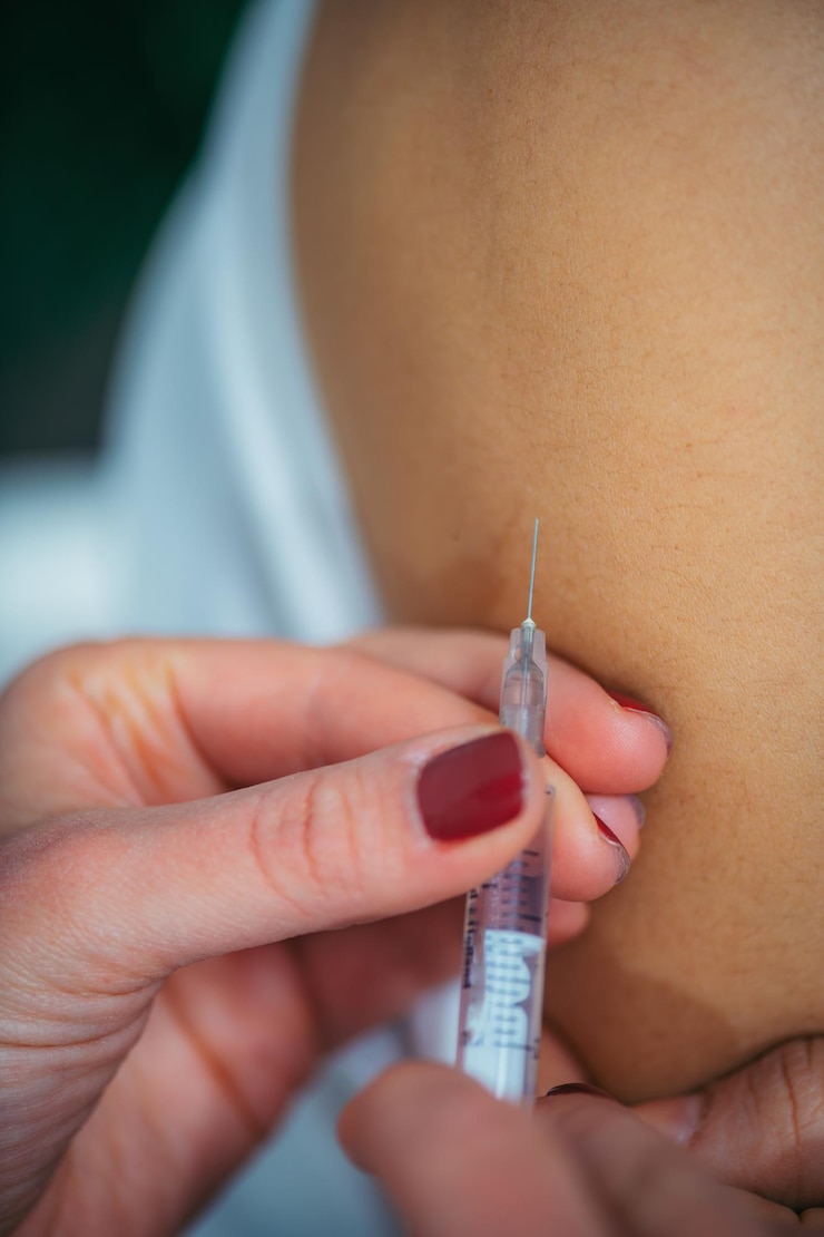 Foto médica inyectando una jeringa en el hombro de una mujer en el hospital