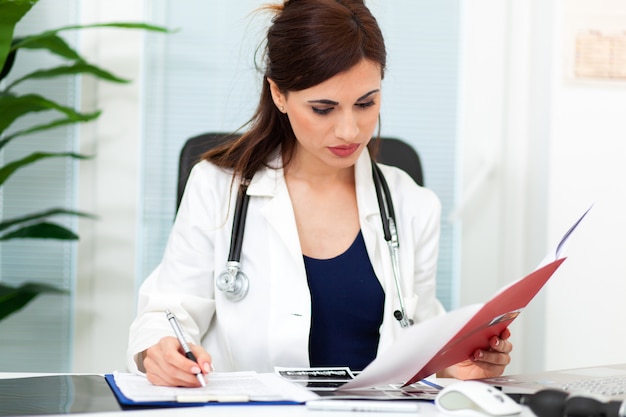 Foto médica, lendo o arquivo do paciente na área de transferência na mesa de escritório