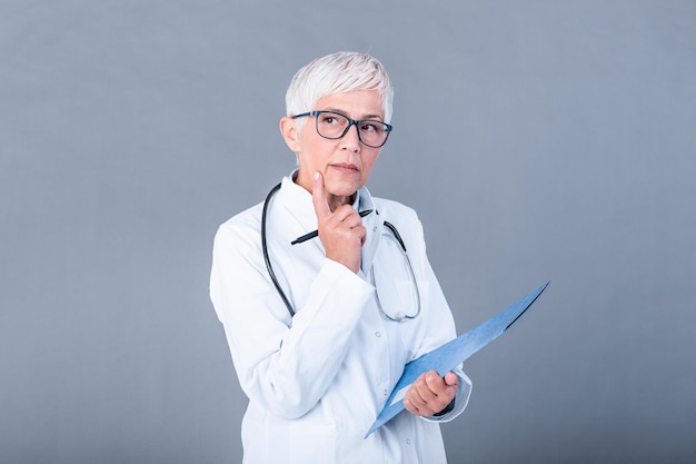 Médica madura com estetoscópio e clipboard pensando em diagnóstico médico Conceito de medicina e cuidados de saúde