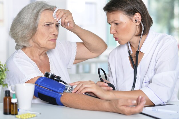 Médica mede a pressão de sua paciente sênior